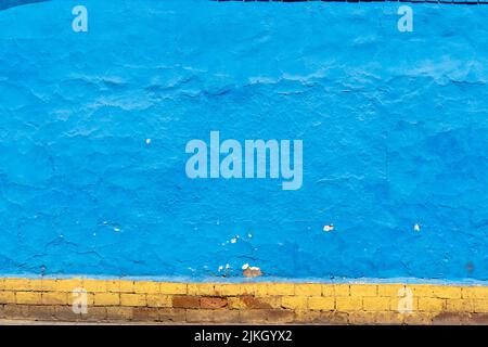 Eine gesprungene blaue Wand mit Backstein aus dem Balg Stockfoto