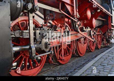 Die rot lackierten Räder einer Dampflokomotive auf den Gleisen Stockfoto