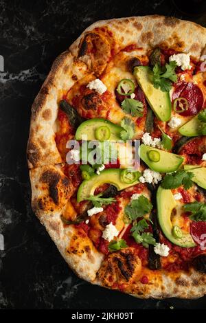 Eine Nahaufnahme von köstlicher Pizza mit Avocado-Scheiben und Käse Stockfoto