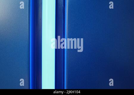 Eine Struktur aus blauer Wand mit hellblauem Neonstreifen Stockfoto
