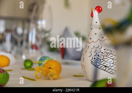 Ein schöner Schuss dekorativer Ostereier und ein Keramikhuhn auf einem Tisch Stockfoto