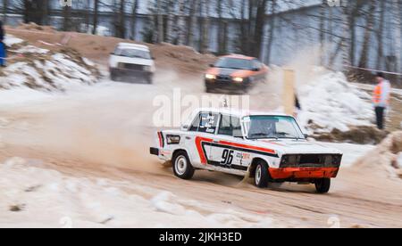 Ein Rennwagen auf der Strecke während eines Rallycross-Eisrennens in Estland im selektiven Fokus mit anderen Fahrzeugen im Hintergrund verschwommen Stockfoto