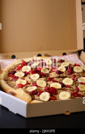 Eine vertikale Aufnahme eines Schokoladenaufstrich überzogene Pizzateig mit Bananen-, Erdbeer- und Haselnussüberzug Stockfoto