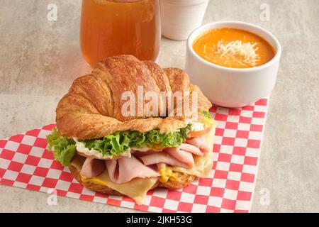 Ein köstliches Schinken- und Käsecroissant mit Sauce und Saft Stockfoto