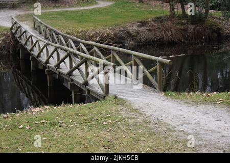 Eine kleine Holzbrücke über einen verschmutzten Fluss Stockfoto