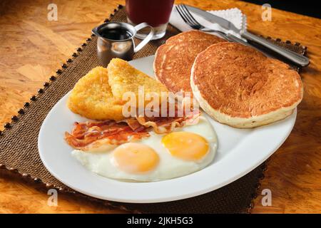 Ein Nahaufnahme eines amerikanischen Frühstücks mit Pfannkuchen, Speck, Eiern und Hashbraun Stockfoto