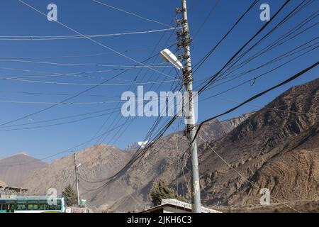 Straßenlaternen auf den Straßen der Stadt Jomsom. Drähte und elektrische Laterne vor der Kulisse der Berge. Himalaya, Nepal Stockfoto