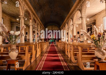 Die Menschen am Altar einer schönen Kirche mit rotem Teppich und Bänken in Chonchi, Chiloe, Chile Stockfoto