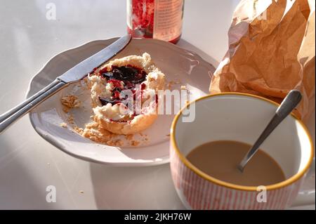 Eine Nahaufnahme eines Brotaufstrich mit Butter und Marmelade auf einem Teller neben einer Tasse Kaffee auf weißem Hintergrund - Konzept des Frühstücks Stockfoto