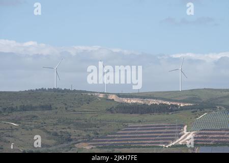 Ein Blick auf das Land in Sao Juliao do Tojal mit Sonnenkollektoren und Windkraftanlagen Stockfoto