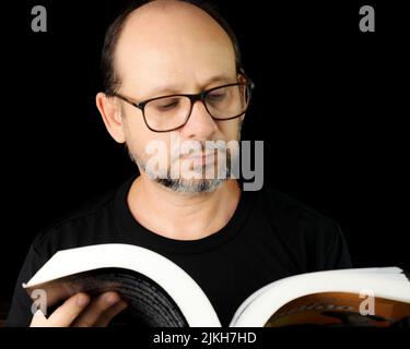 Porträt eines bärtigen Mannes mit Brille vor schwarzem Hintergrund. Salvador, Bahia, Brasilien. Stockfoto