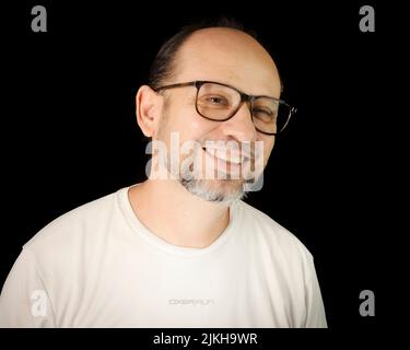 Porträt eines bärtigen Mannes mit Brille vor schwarzem Hintergrund. Salvador, Bahia, Brasilien. Stockfoto