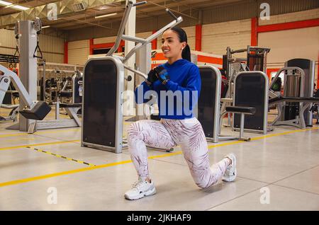 Eine hispanische Frau, die im Fitnessstudio mit Geräten arbeitet Stockfoto