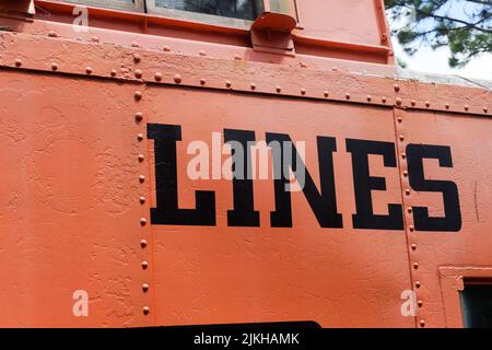 Eine Nahaufnahme des Wortes „LINIEN“, das in Schwarz auf einer orangefarbenen Metalloberfläche gemalt wurde Stockfoto