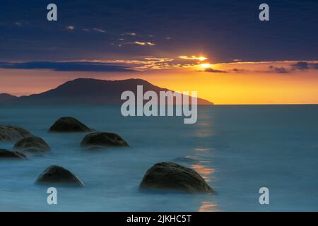 Eine lange Meereslandschaft unter einem dramatischen Sonnenuntergangshimmel Stockfoto