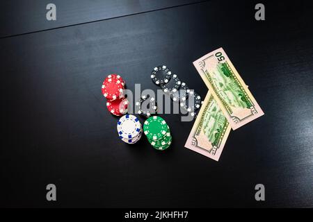 Eine Draufsicht auf Stapel von Pokerchips mit Geld auf einem schwarzen Tisch Stockfoto