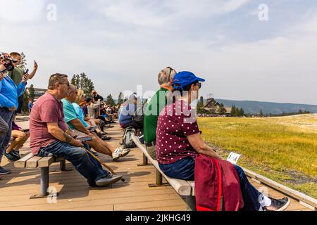 Die Menschen, die auf den Ausbruch des Geysir Old Faithful im Yellowstone National Park warten. Stockfoto