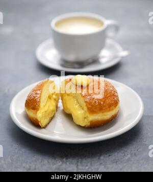 Hausgemachte Bomboloni gefüllt mit Pudding, italienische gefüllte Donuts. Stockfoto