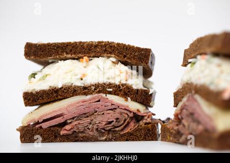 Ein in zwei Hälften geschnittenes Pastrami-Sandwich, das alle Zutaten auf weißem Hintergrund darstellt Stockfoto