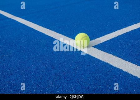 Nahaufnahme eines Tennisballs auf der weißen Linie eines Paddle-Tennisplatzes Stockfoto