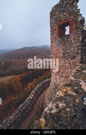 Eine vertikale Aufnahme der Ruinen der Burg Csesznek in Ungarn an einem nebligen Tag Stockfoto