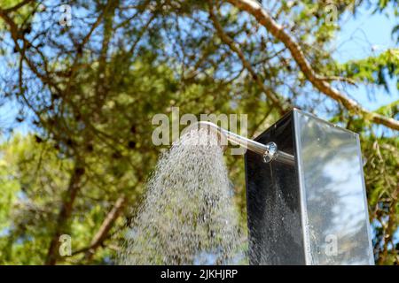 Ein niedriger Winkel des Wassers, das aus der Dusche auf einen Strand strömt Stockfoto