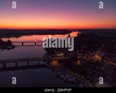 Ein Blick auf rosa und orange Sonnenuntergang über einer kleinen Stadt an einem See in Warmia, Polen Stockfoto