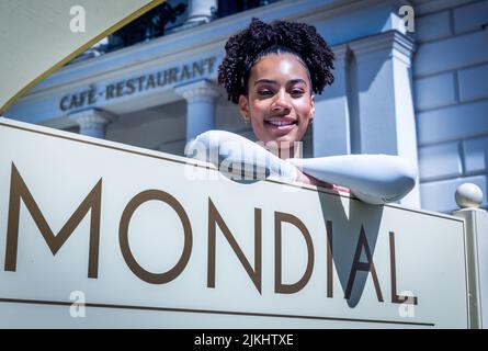 Schwerin, Deutschland. 02. August 2022. Joy Ewulu in der Rolle von Lara Hildebrand steht während einer Drehpause für die neue ZDF-Serie „Hotel Mondial“ hinter dem Hotelschild. Das imaginäre 4-Sterne-Hotel 'Mondial', das auf eine lange Tradition zurückblicken kann, bildet den Rahmen für das Grundstück. Nach Angaben der Produktionsfirma wird die erste Staffel aus zwölf Episoden bestehen und im nächsten Jahr mittwochs ausgestrahlt. Quelle: Jens Büttner/dpa/Alamy Live News Stockfoto