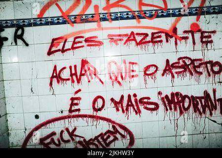 Rote Graffiti-Wörter auf Portugiesisch auf einer alten schmutzigen weißen gefliesten Wand gemalt Stockfoto