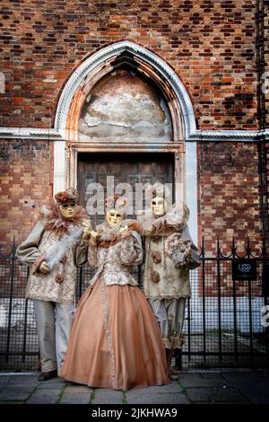 Eine vertikale Aufnahme von Menschen, die Masken und Kostüme für den venezianischen Karneval in Italien tragen Stockfoto