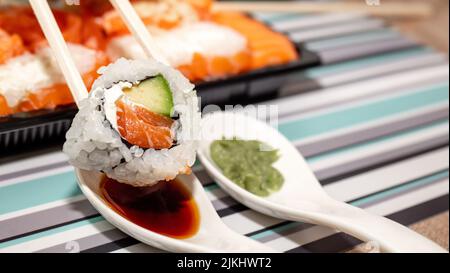 japanische Küche, Lebensmittelzustellung bei Coronavirus, Sushi in einem schwarzen Behälter auf einem Holztisch, Lieferung und Bestellung Stockfoto