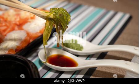 Algensalat in einem schwarzen Behälter auf einem Holztisch, Lieferung und Bestellung Stockfoto