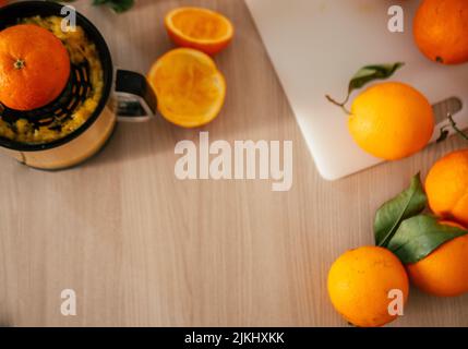 Gepresster Orangensaft und frische Orangenfrüchte auf einem Holztisch Stockfoto