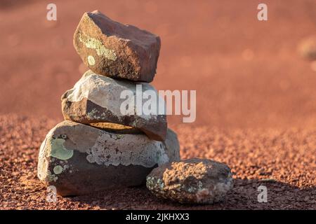 Eine Nahaufnahme von Steinen, die auf dem roten Boden übereinander gestapelt sind. Ausgewählter Fokus. Stockfoto