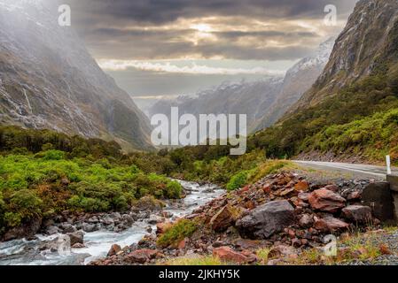 Bergiger Monkey Creek, der durch eine beeindruckende Landschaft neben dem Milford Sound Highway, Südinsel Neuseelands, fließt Stockfoto