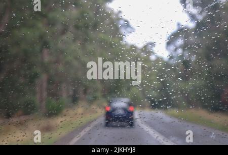 Ein fahrend Auto bei nassem Wetter mit Regentropfen auf der Windschutzscheibe Stockfoto