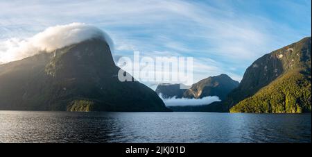 Sonne geht über Doubtful Sound auf, Wolken hängen tief auf den Bergen, Südinsel von Neuseeland Stockfoto