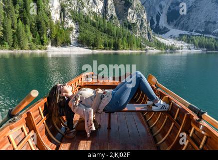 Eine junge Frau, die sich in einem Holzboot auf dem See Prags in Italien entspannt Stockfoto