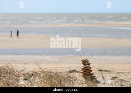 Eine selektive Fokusaufnahme von gestapelten Steinen an einem Sandstrand Stockfoto
