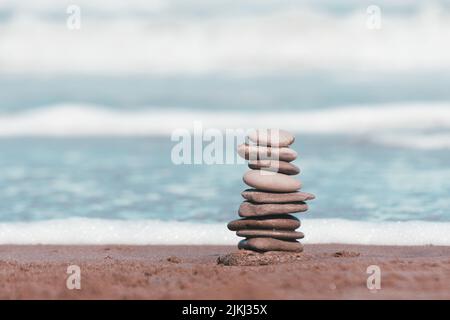 Ein flacher Fokus von Strandsteinen, die auf dem Hintergrund des Meeres aufeinander gestapelt sind Stockfoto