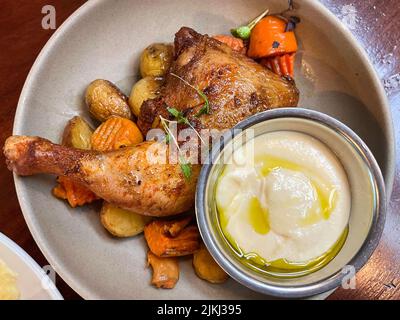 Gebackene Hähnchenschenkel mit gegrillten Kartoffeln auf einem weißen Teller Stockfoto