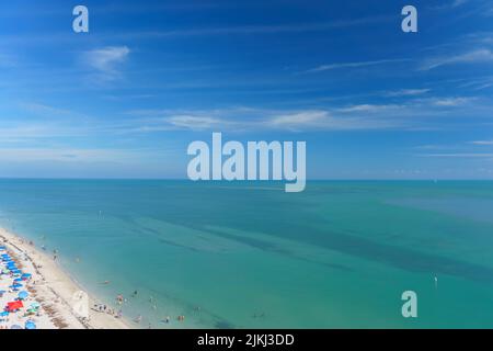 Eine Luftaufnahme des schönen Sandstrands an der Küste, der unter dem wolkig-blauen Himmel glänzt Stockfoto