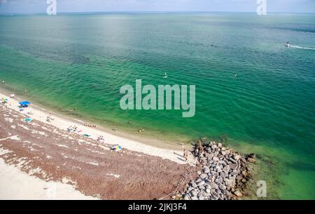 Eine Luftaufnahme des schönen Sandstrands an der Küste, der unter dem blauen Himmel glänzt Stockfoto