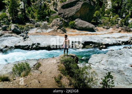 Ein junger hispanischer Kerl in Sonnenbrille, der an einem Fluss in Argentinien steht Stockfoto