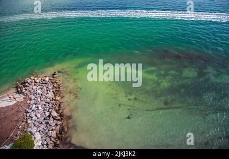 Eine Luftaufnahme des schönen Sandstrands an der Küste, der unter dem blauen Himmel glänzt Stockfoto
