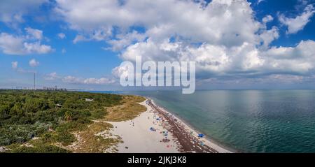 Eine Luftaufnahme des schönen Sandstrands an der Küste, der unter dem wolkig-blauen Himmel glänzt Stockfoto
