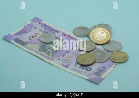 Die indische Währung - die 100 Rupie Note mit indischen Münzen. 1, 5, 10 Rupien-Münzen auf blauem Hintergrund Stockfoto