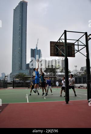 Eine schöne Aufnahme von Kindern, die auf dem Schulhof in Hongkong, China, Basketball spielen Stockfoto