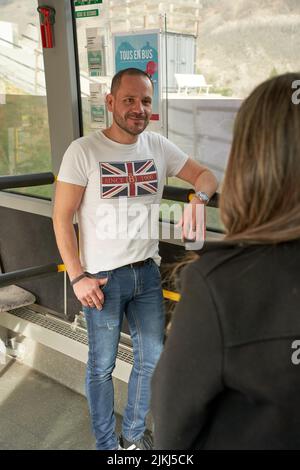Eine vertikale Aufnahme von zwei Fahrgästen, die während der Fahrt in einem Bus stehen und sprechen Stockfoto