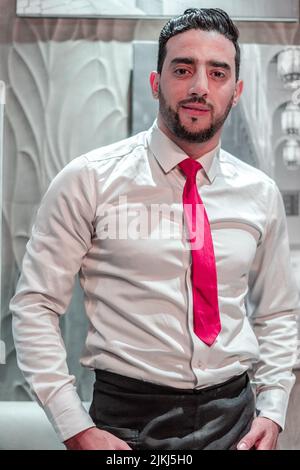 Ein hübscher Kellner, der sich mit der Uniform des Jobs verkleidet Stockfoto